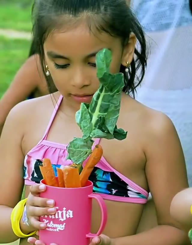 Niña con la taza de la granja Kalomai llena de zanahorias